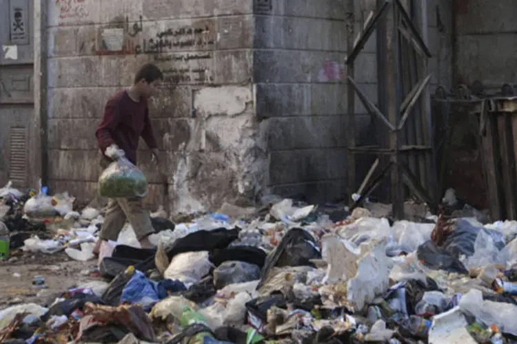 Jovem caminha em meio ao lixo na cidade síria de Alepo nesta terça-feira (Mahmoud Hassano/Reuters)