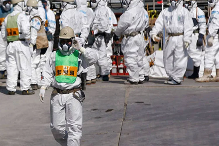 
	Trabalhadores com roupa de seguran&ccedil;a na usina nuclear de Fukushima: o governo pretende tamb&eacute;m assumir o custo das instala&ccedil;&otilde;es necess&aacute;rias para armazenar e descontaminar a terra
 (REUTERS/Issei Kato/Files)
