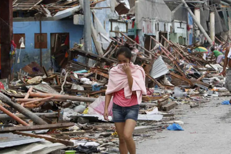 
	Mulher caminha entre destro&ccedil;os de Tacloban: escala do desastre e desafios para entregar ajuda faz com que poucas pessoas de Tacloban tenham recebido aux&iacute;lio
 (Romeo Ranoco/Reuters)