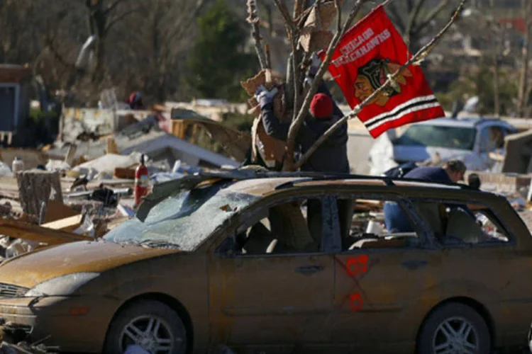 Moradores erguem uma bandeira do Chicago Blackhawks encontrada em meio aos destroços deixado por um tornado em Washington, Illinois (Jeff Haynes/Reuters)