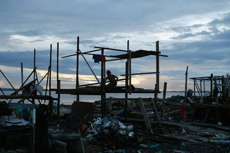 
	Sobrevivente do tuf&atilde;o nas Filipinas constr&oacute;i abrigo para sua fam&iacute;lia: pelo menos 323.454 casas ficaram destru&iacute;das e outras 324.706 sofreram danos
 (REUTERS/Erik De Castro)
