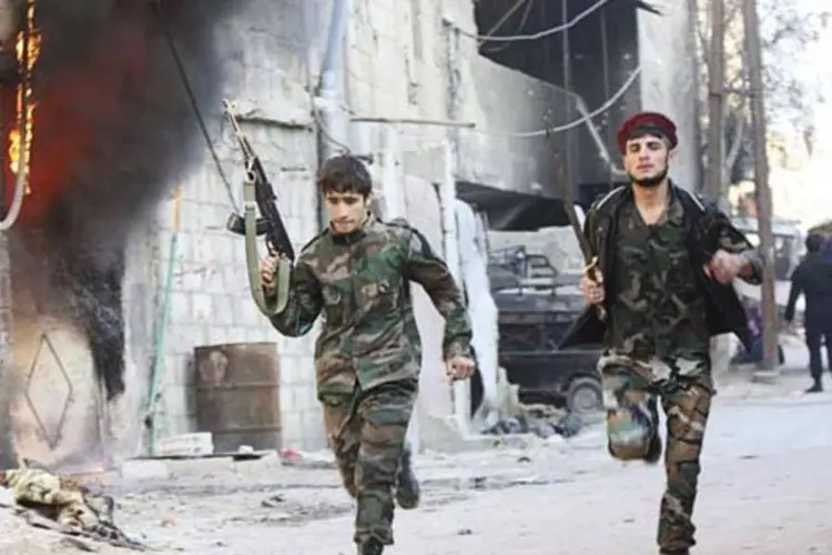Combatentes xiitas integrantes das forças leais ao presidente sírio, Bashar al-Assad, correm nas ruas desertas do bairro de Hujaira, no sul de Damasco (Alaa Al-Marjani/Reuters)