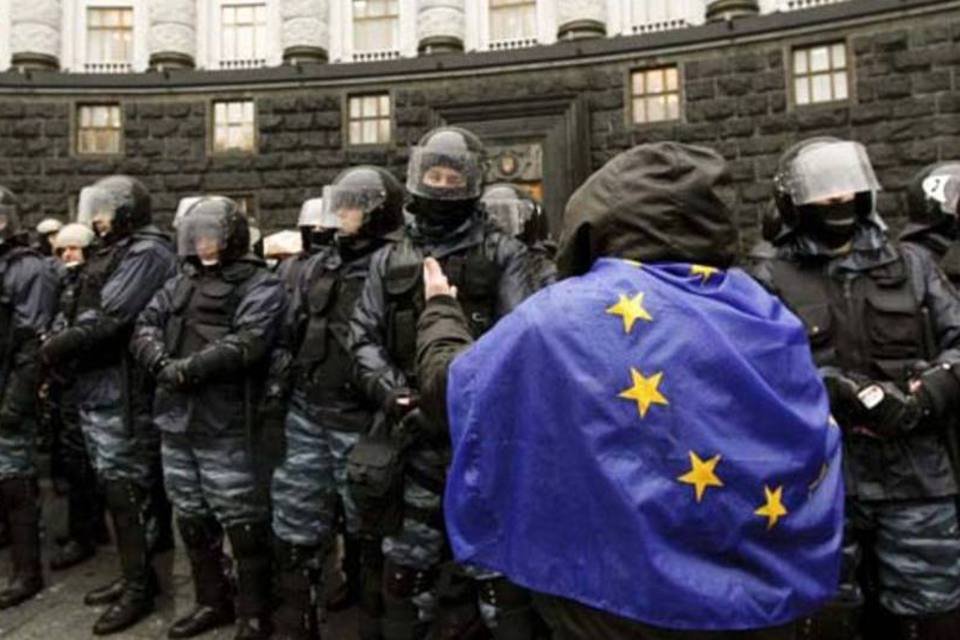 Ucraniano com uma bandeira da UE sobre os ombros anda perto dos policiais durante uma manifestação em apoio à integração com o bloco (Vasily Fedosenko/Reuters)