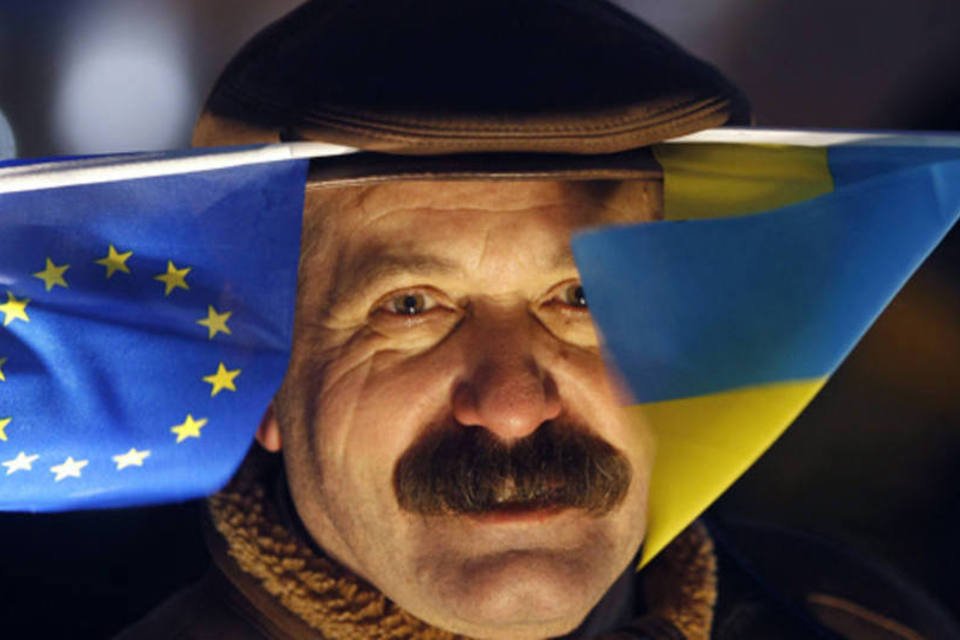 Homem é visto com bandeiras da União Europeia e da Ucrânia durante manifestação para apoiar a integração do país com o bloco, em Kiev (Vasily Fedosenko/Reuters)