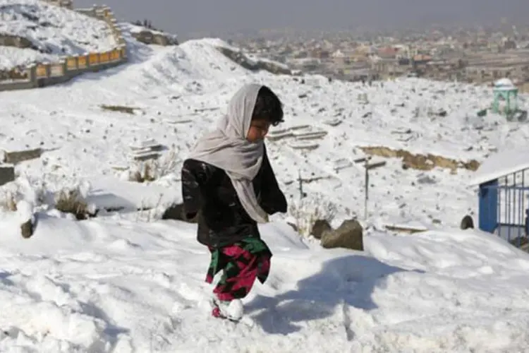 Uma menina anda em um cemitério coberto pela neve em Cabul, Afeganistão (Mohammad Ismail/Reuters)