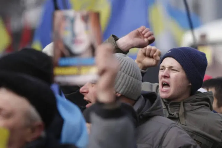 Manifestantes agitam bandeiras e gritam palavras de ordem em frente ao parlamento, em Kiev (Stoyan Nenov/Reuters)