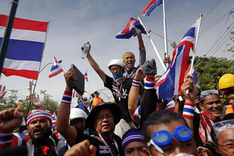 Manifestantes antigoverno agitam bandeiras enquanto comemoram a entrada no complexo da sede da polícia metropolitana, em Bangkok, Tailândia (Damir Sagolj/Reuters)