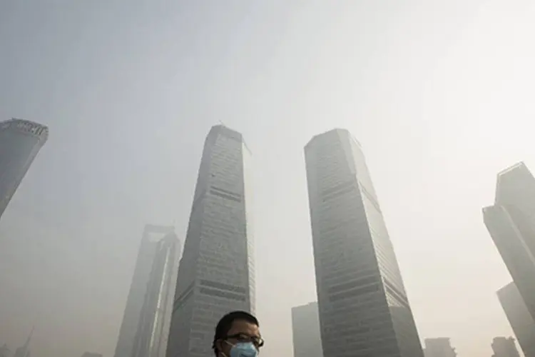 Homem usando máscara atravessa uma ponte sob intensa poluição no distrito comercial de Xangai, na China (Aly Song/Reuters)