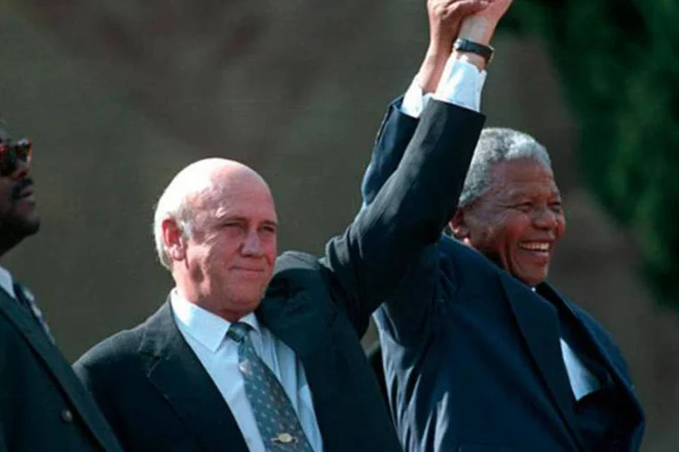 Nelson Mandela (à direita) e o segundo ex-vice-presidente sul-africano F.W. De Klerk (centro) acenam para uma multidão após a posse presidencial, em maio de 1994 (REUTERS/Juda Ngwenya)
