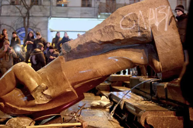 Manifestantes ucranianos observam estátua de líder soviético Vladimir Lenin derrubada durante protesto na capital Kiev (Maks Levin/Reuters)