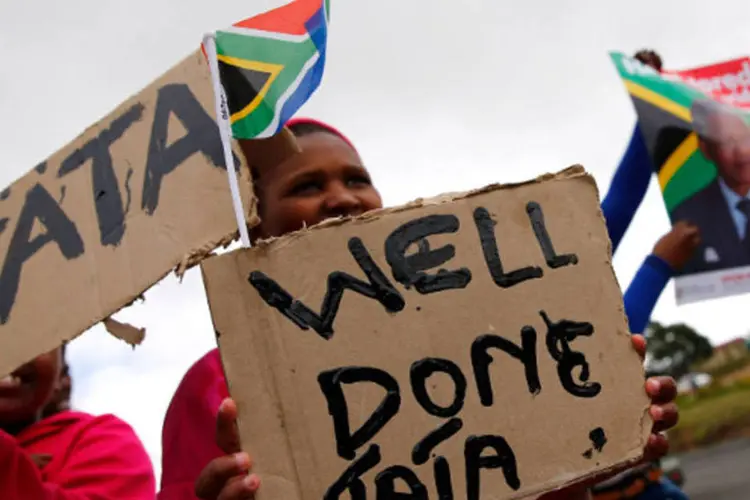 Sul-africanos seguram cartazes enquanto esperam o cortejo carregando o corpo de Nelson Mandela, no vilarejo de Qunu  (Kai Pfaffenbach/Reuters)