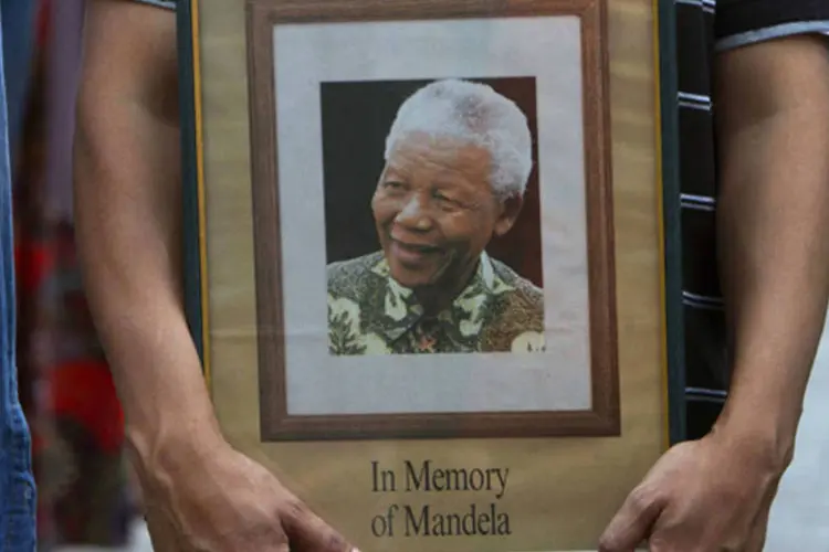 Homem segura quadro com a foto do ex-presidente sul-africano Nelson Mandela enquanto assiste ao funeral televisionado do ex-líder, na Cidade do Cabo (Mark Wessels/Reuters)