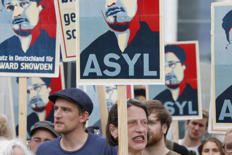 
	Manifestantes seguram cartazes durante protesto em apoio a Edward Snowden, em Berlim
 (Tobias Schwarz/Reuters)