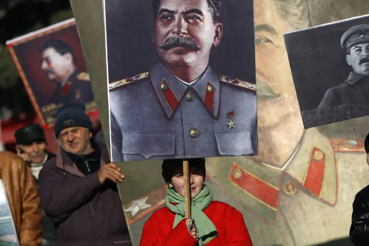 Pessoas carregando retratos do ditador soviético Joseph Stalin durante manifestação na cidade de Gori, cidade natal do ditador (David Mdzinarishvili/Reuters)