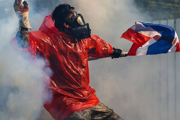 
	Um manifestante antigoverno joga uma bomba de g&aacute;s em dire&ccedil;&atilde;o a policiais durante confrontos no centro de Bangcoc: oito pessoas morreram e dezenas ficaram feridas desde outubro
 (REUTERS/Athit Perawongmetha)