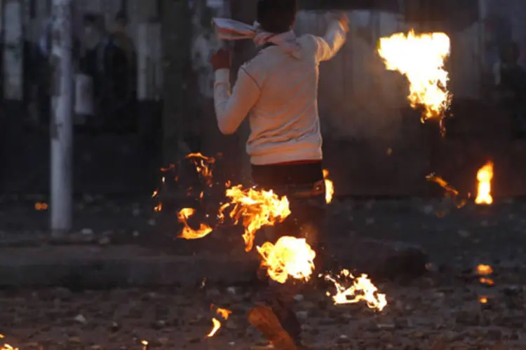 Simpatizante do exército e da polícia joga de volta um coquetel molotov sobre estudantes da Universidade Al-Azhar, que apoiam a Irmandade Muçulmana e o presidente deposto Mohamed Mursi (Amr Abdallah Dalsh/Reuters)