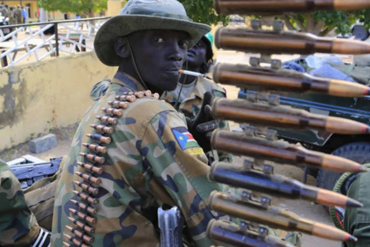 Soldado do exército do Sudão do Sul fuma perto de metralhadora na cidade de Malakal, perto da capital Juba (James Akena/Reuters)