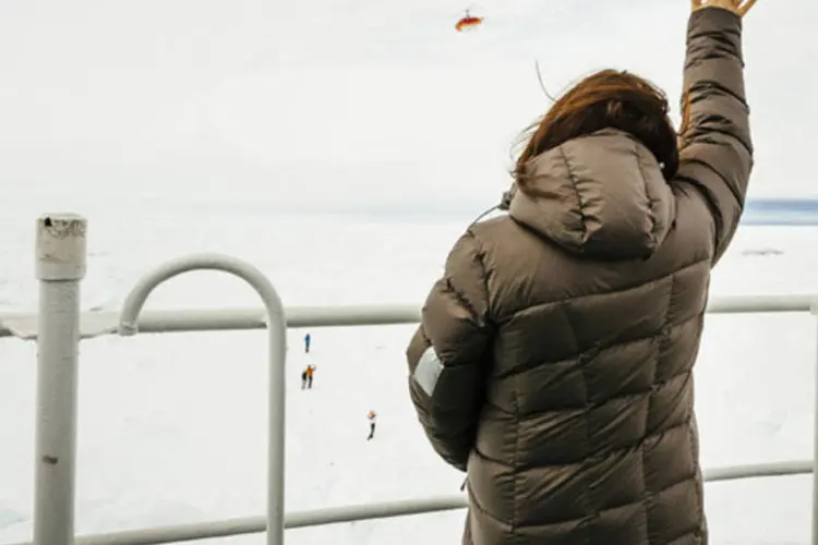 
	Nicole De Losa, uma das passageiras a bordo do navio russo Akademik Shokalskiy, acena para o helic&oacute;ptero enviado pelo quebra-gelo chin&ecirc;s Xue Long (Drag&atilde;o da Neve), na Ant&aacute;rtica
 (Andrew Peacock/Reuters)