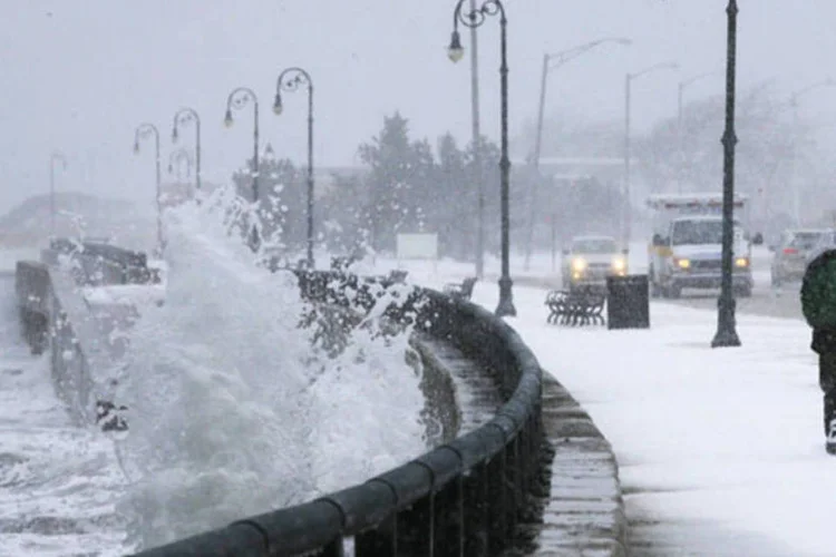 Homem corre enquanto ondas batem no quebra-mar durante nevasca de inverno, em Massachusetts, EUA (Brian Snyder/Reuters)
