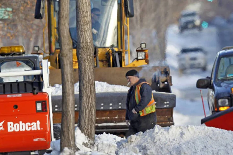 Trabalhadores usam uma variedade de tratores para remover a neve da calçada no sul de Minneapolis, nos Estados Unidos (Eric Miller/Reuters)
