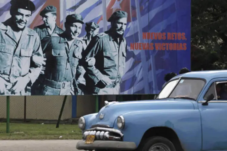 Carro passa por um outdoor com as imagens de  Ernesto "Che" Guevara, Raul Castro e Fidel Castro, em Havana, capital de Cuba  (Enrique de la Osa/Reuters)