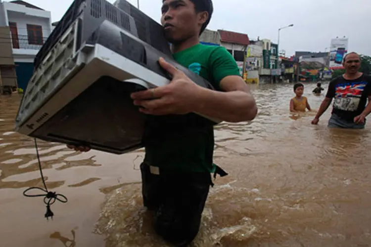 Homem tenta salvar televisão de enchente na Indonésia (REUTERS/Supri)