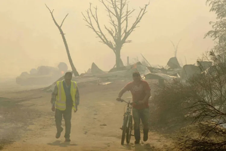 Moradores caminham por uma área atingida pelos incêndios florestais na cidade rural de Flórida, perto de Concepcion, no Chile (Jose Luis Saavedra/Reuters)