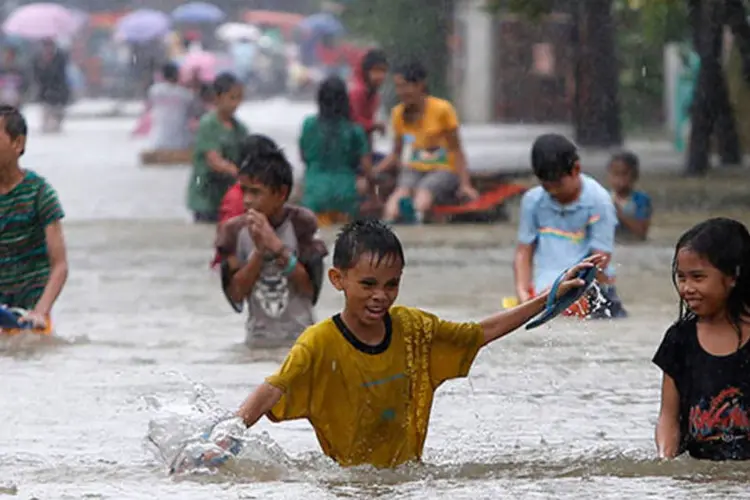 
	Crian&ccedil;as atravessam enchente nas Filipinas: 460 mil pessoas em 14 prov&iacute;ncias filipinas foram atingidas pelas fortes chuvas
 (REUTERS/Erik De Castro)
