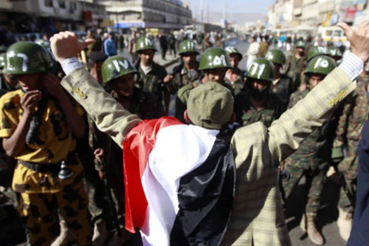 Manifestante anti-governo em frente a tropa de choque da polícia, em um protesto em Sanaa, no Iêmen (Mohamed al-Sayaghi/Reuters)