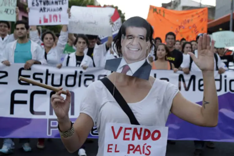 Estudante universitário, com a máscara do presidente Horacio Cartes, marcha para protestar contra o aumento do transporte público, em Assunção (Jorge Adorno/Reuters)