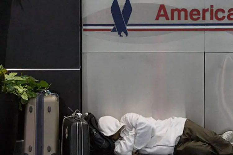 
	Passageiro dorme sob o logo da American Airlines no Aeroporto de Nova York: cerca de 3 mil voos comerciais foram cancelados na ter&ccedil;a-feira&nbsp;
 (REUTERS/Andrew Kelly)