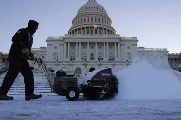 Trabalhador limpa a neve em uma calçada em frente ao prédio do Capitólio, em Washington  (Jonathan Ernst/Reuters)