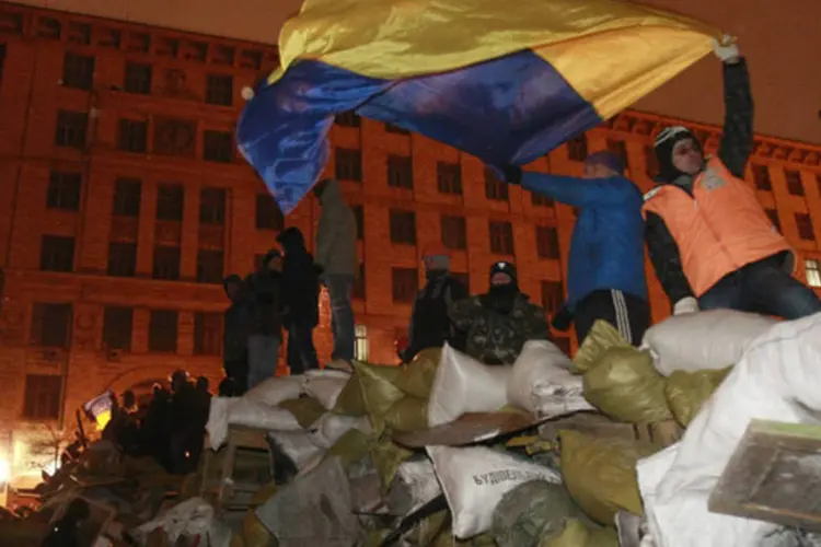 Manifestantes antigoverno, que montaram uma barricada durante protesto em Kiev, exibem uma bandeira nacional ucraniana nesta quinta-feira (Gleb Garanich/Reuters)