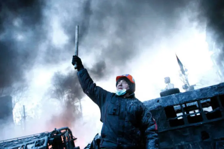 
	Homem em barricada perto do local de conflitos entre manifestantes contra o governo e tropas de choque em Kiev
 (David Mdzinarishvili/Reuters)