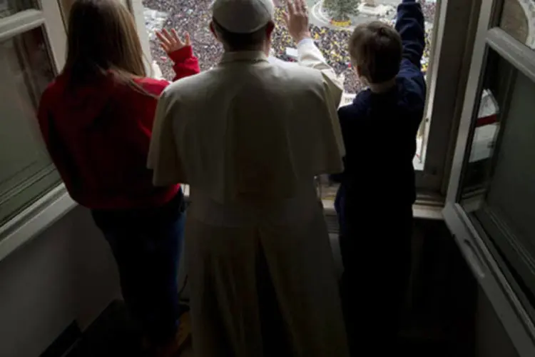 Papa Francisco acena com duas crianças após soltarem pombas durante missa na Praça de São Pedro, Vaticano, no dia 26 de janeiro de 2014 (Osservatore Romano/Reuters)
