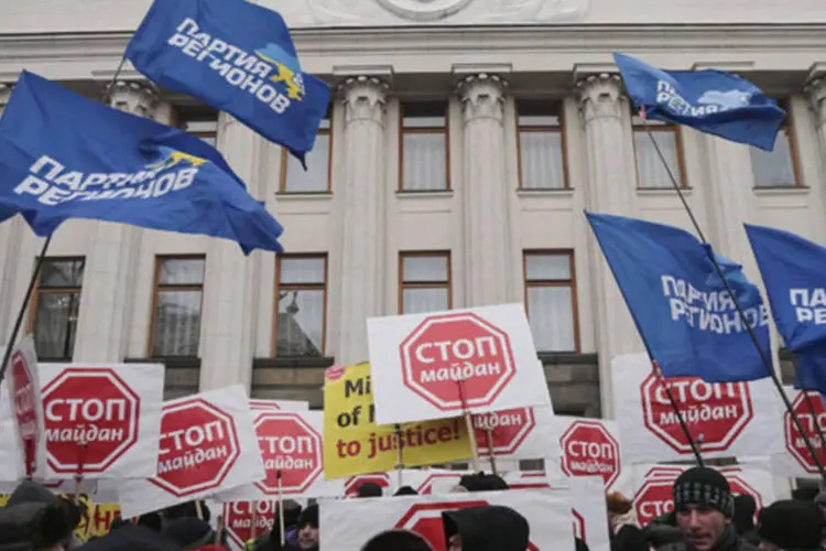 Apoiadores do presidente ucraniano Viktor Yanukovich levantam cartazes durante protesto em frente ao Parlamento, em Kiev (Konstantin Chernichkin/Reuters)