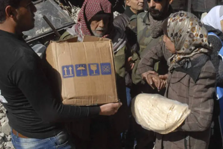 Moradores recebem alimentos da UNRWA, agência da ONU, no campo de Yarmouk, em um dos subúrbios de Damasco (SANA/Divulgação via Reuters)