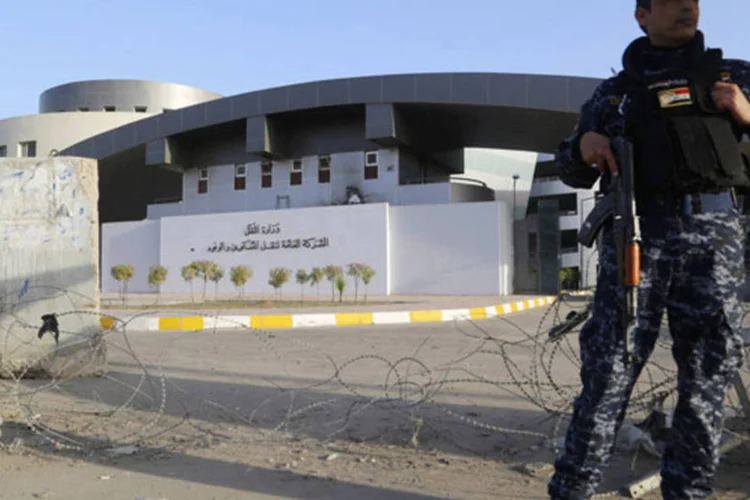 Policial iraquiano monta guarda em frente ao prédio do Ministério do Trabalho, após um ataque com homens-bomba, em Bagdá (Thaier Al-Sudani/Reuters)