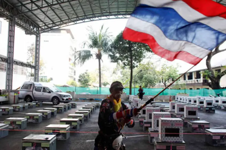 Um manifestante anti-governo balança bandeira da Tailândia próximo a urnas das eleições (REUTERS/Nir Elias)