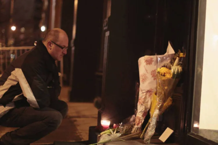 Homem deixa flores em memória ao ator Philip Seymour Hoffman em frente ao apartamento onde foi encontrado morto, em Manhattan (John Taggart/Reuters)