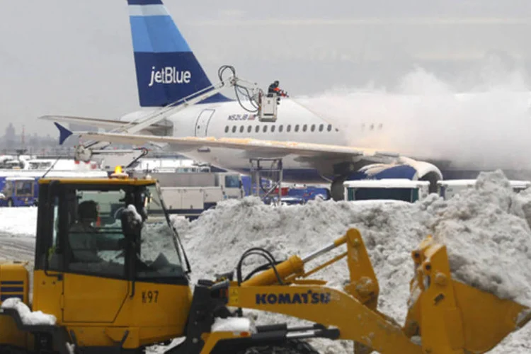 
	Trabalhador limpa a neve de um terminal do aeroporto LaGuardia: quase 2.600 voos foram cancelados na manha desta quarta-feira
 (Joshua Lott/Reuters)