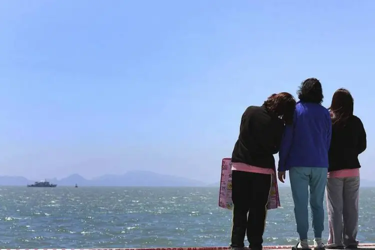 Familiares de passageiros desaparecidos em balsa sul-coreana olham para o mar enquanto esperam notícias da operação de busca e resgate no porto de Jindo  (REUTERS/Yonhap)
