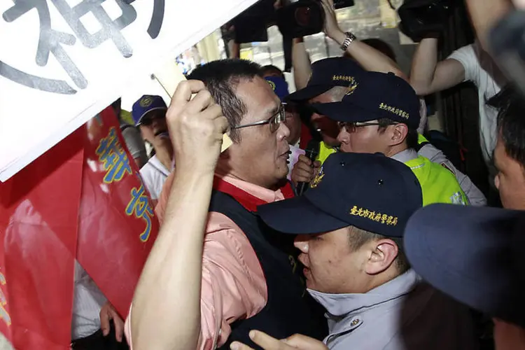 Ativista que segura cartaz durante protesto anti-China entra em confronto com a polícia em frente ao escritório econômico e cultural do Vietnã (REUTERS/Pichi Chuang)