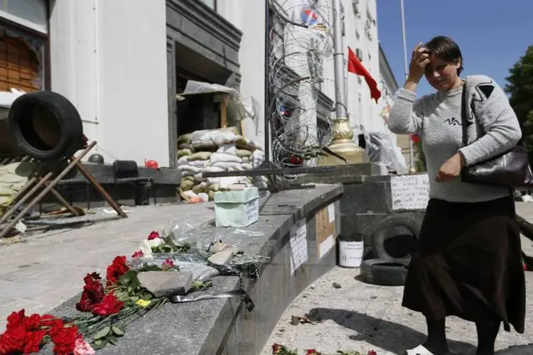 Mulher coloca flores próximo a local de uma explosão em um prédio administrativo na Ucrânia  ( REUTERS/Gleb Garanich)