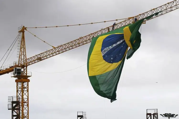 Trabalhadores tentam consertar bandeira do lado de fora da Arena Castelão, em Fortaleza (REUTERS/Kai Pfaffenbach)