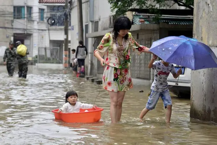 Mulher anda com crianças em rua alagada após forte tempestade em Changzhou, províncias de Jiangsu (REUTERS/Stringer)