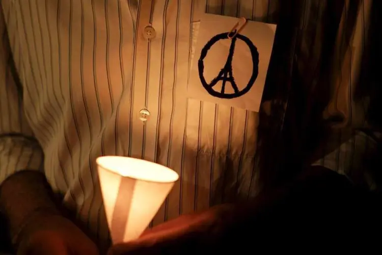 
	Homem com o &quot;Peace for Paris&quot; no peito segura uma vela em tributos &agrave;s v&iacute;timas dos atentados terroristas a Paris
 (REUTERS/Athit Perawongmetha)