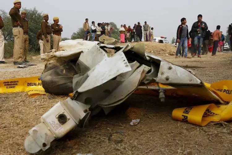 Curiosos e policiais ao lado dos destroços do avião: aeronave colidiu contra um muro e explodiu, matando os 10 passageiros (REUTERS/Adnan Abidi)