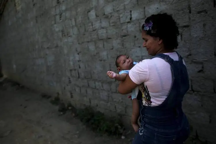 Jackeline, 26, segura seu filho Daniel, de 4 meses de idade e nascido com microcefalia, enquanto andam na rua em direção a sua casa em Olinda (REUTERS/Nacho Doce)