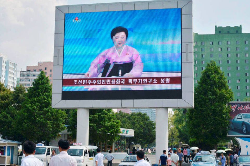 Pessoas passam em frente a um telão que transmite o anúncio do governo da Coreia do Norte de mais um teste nuclear (Kyodo/via REUTERS)